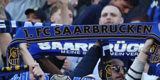 Fans des 1. FC Saarbrücken stehen auf der Tribüne und halten ihren Schal hoch (Foto: picture alliance / Fußball-News Saarland | Fabian Kleer)