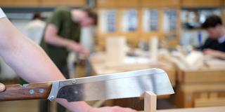 Auszubildende sägen in einer Lehrwerkstatt an ihren Holzwerkstücken (Foto: picture alliance/dpa | Bernd Weissbrod)