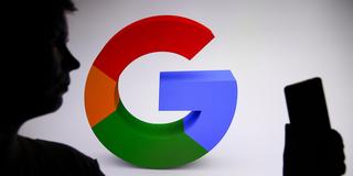 Eine Person hält ein Smartphone vor einem Google Logo (Symbolbild) (Foto: picture alliance / NurPhoto | Klaudia Radecka)