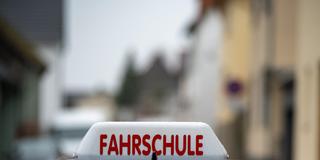 Schild einer Fahrschule, das auf einem Autodach montiert ist, welches von zahlreichen Regentropfen bedeckt ist.  (Foto: picture alliance / W2Art / Thorsten Wagner)