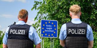 Zwei Bundespolizsten stehen vor einem Schild auf dem "Bundesrepublik Deutschland" steht. (Foto: picture alliance/dpa | Patrick Pleul)
