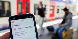Illustration. Eine Information zum Kauf des Deutschlandtickets ist auf dem Display eines Smartphones am Bahnhof. (Foto: picture alliance/dpa | Julian Stratenschulte)