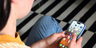 Eine Jugendliche sitzt mit einem Smartphone auf dem Boden (Foto: picture alliance/dpa | Elisa Schu)