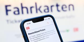 Eine Person hält am Hauptbahnhof ein Smartphone in der Hand, auf dessen Display eine Information zum Kauf des Deutschlandtickets zu sehen ist (Foto: picture alliance/dpa | Julian Stratenschulte)