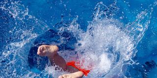 Ein Badegast springt ins Schwimmbadwasser (Foto: picture alliance/dpa | Michael Reichel)