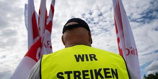 Ein NGG-Mitglied trägt eine Weste mit der Aufschrift «Wir streiken». (Foto: picture alliance/dpa | Peter Kneffel)