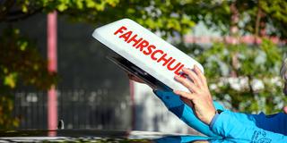 Ein Fahrlehrer hantiert mit dem Dachschild eines Fahrschulautos (Foto: picture alliance/dpa | Klaus-Dietmar Gabbert)