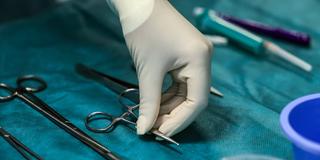 Eine Hand greift nach einer Klemme im Operationssaal (Foto: picture alliance/dpa | Oliver Berg)
