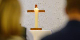 Eine Kerze brennt vor einem Kreuz (Foto: picture alliance/dpa | Klaus-Dietmar Gabbert)