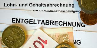 Auf Lohn- und Gehaltsabrechnungen (Entgeltabrechnungen) liegen Euromünzen und Eurogeldscheine (Foto: dpa/Arno Burgi)