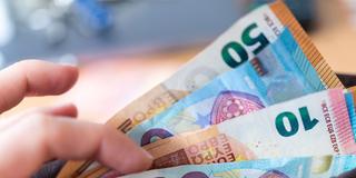 Eine Frau hält eine Geldbörse mit Banknoten in der Hand. (Foto: picture alliance/dpa | Monika Skolimowska)