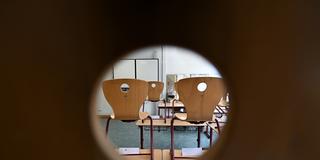 In einem Klassenraum in die Stühle hochgestellt. (Foto: picture alliance/dpa | Arne Dedert)