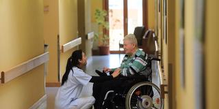 Pflegeassistentin aus China, spricht mit Bewohnerin im Seniorenheim. (Foto: picture alliance / dpa | Jens Wolf)