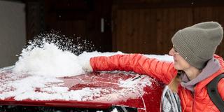 Eine Frau fegt den Schnee von ihrem Auto (Foto: picture alliance/KEYSTONE | PETER SCHNEIDER)