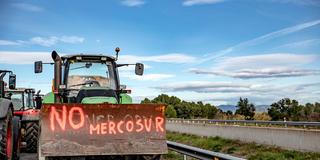 Ein Traktor steht zum Protest auf der Landstraße mit einem Graffiti gegen das Mercosur-Abkommen (Foto: picture alliance/dpa/ZUMA Press Wire | Oriol Leza)