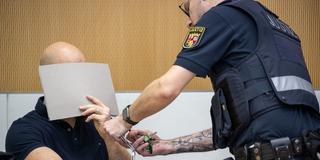 Ein Justizbediensteter löst im Landgericht Trier dem wegen Mordes verurteilten 35-Jährigen Mann aus dem Nordsaarland die Handfesseln. (Foto: picture alliance/dpa | Harald Tittel)