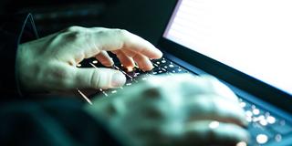 Jemand tippt mit den Fingern auf einer beleuchteten Laptop-Tastatur (Foto: picture alliance/dpa | Philip Dulian)