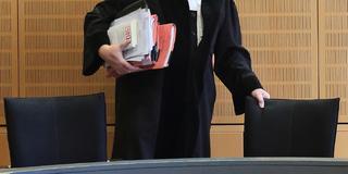 Ein Richter rückt sich in einem Verhandlungssaal seinen Stuhl zurecht. (Foto: picture alliance / dpa | Jens Wolf)