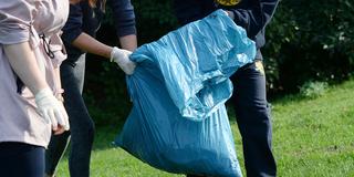 Kinder halten einen blauen Müllsack in den Händen. (Foto: picture alliance / dpa | Jens Kalaene)