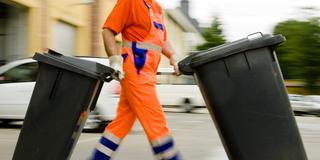 Ein Müllmann bringt Restmülltonnen weg (Foto: dpa/Frank Rumpenhorst)