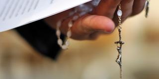 Ein Priester hält einen Rosenkranz (Foto: dpa)