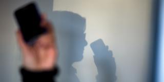 Ein Telefon vor einem Schatten an der Wand (Foto: picture alliance / dpa | Arno Burgi)