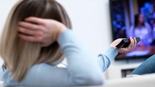 Eine Frau sitzt auf einer Couch und guckt Fernsehen (Foto: dpa)