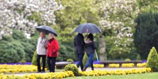 Spaziergänger schützen sich  bei wechselhaftem Wetter mit Regenschirmen.  (Foto: picture alliance / Caroline Seidel/dpa )