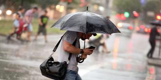 Passanten kreuzen in einem Regenschauer die Straße (Foto: picture alliance / Martin Gerten / dpa)