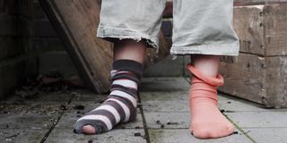 Ein junges Mädchen mit Löchern in den Socken. (Foto: dpa)