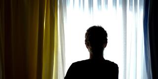 Eine junge Frau steht in dem Zimmer eines Frauenhauses. (Foto: picture alliance / Peter Steffen/dpa | Peter Steffen)