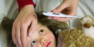 Eine Mutter kontrolliert mit einem Fieberthermometer die Temperatur ihrer kranken Tochter (Foto: picture alliance / Patrick Pleul/dpa | Patrick Pleul)
