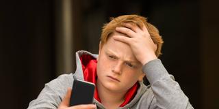 Ein Junge schaut traurig auf sein Smartphone (Foto: picture alliance / PantherMedia | Andriy Popov)