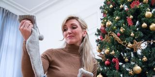 Eine junge Frau packt ihr Weihnachtsgeschenk aus. (Foto: dpa/Christin Klose)