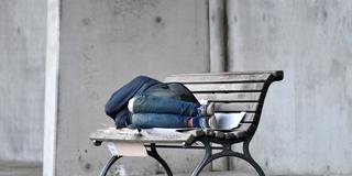 Eine Person schläft auf einer Bank. (Foto: picture alliance/dpa/Paul Zinken)