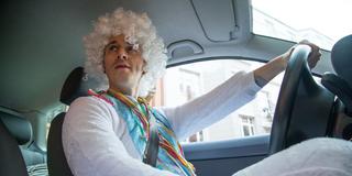 Ein Mann sitzt verkleidet am Steuer eines Autos. (Foto: picture alliance / dpa Themendienst | Christin Klose)