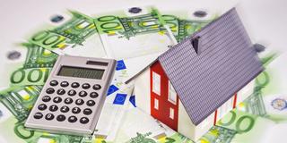 Modell eines Hauses mit Euoscheinen und einem Taschenrechner (Foto: picture alliance / Klaus Ohlenschläger)