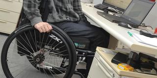 Ein Rollstuhlfahrer an seinem Arbeitsplatz (Foto: dpa)