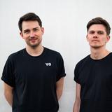 Zwei Männer in schwarzen T-Shirts stehen vor einer grauen Wand (Foto: Pressefoto)