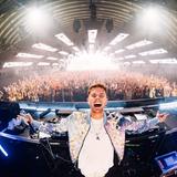 Ein DJ steht an seinem Pult auf einer Bühne. Im Hintergrund ist das Publikum zu sehen. (Foto: Pressefoto)