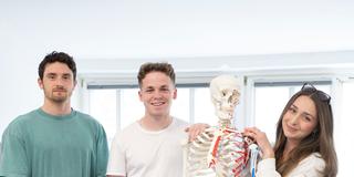Physiotherapie-Azubis im ersten Lehrjahr am Uniklinikum in Homburg stehen neben einem Anatomie-Modell. (Foto: Laura Glücklich/ UKS)
