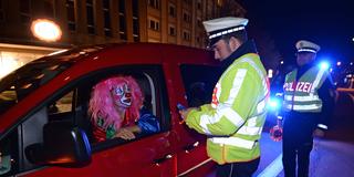 Polizisten kontrollieren eine kostümierte Person im Auto (Foto: picture alliance / dpa | Patrick Seeger)