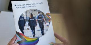 Eine Person hält eine Broschüre in der Hand mit dem Titel "Schutz vor Hetze und Gewalt für Queere Menschen" (Foto: SR)