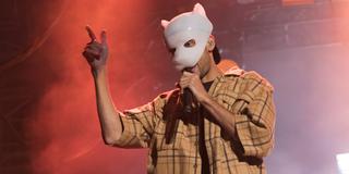 Ein Mann mit einer weißen Maske steht auf der Bühne und singt. (Foto: IMAGO / Christian Grube)