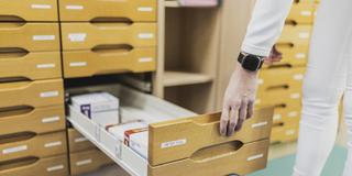 Eine Person öffnet eine Schublade eines Apothekenschranks. Darin sind einige Medikamente, jedoch ist die Schublade nur halb voll. (Foto: picture alliance / photothek | Florian Gaertner)