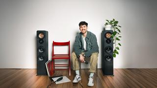 Ein Mann sitzt zwischen zwei Lautsprecherboxen vor einer grauen Wand. (Foto: SR)