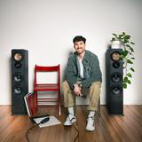 Ein Mann sitzt zwischen zwei Lautsprecherboxen vor einer grauen Wand. (Foto: SR)