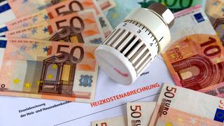 Geldscheine und ein Heizungsthermostat liegen auf einer Heizkostenabrechnung (Foto: picture alliance / dpa | Jens Büttner)