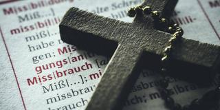 Kreuz auf einem Wörterbuch mit dem Wort "Missbrauch" (Foto: IMAGO / Christian Ohde)