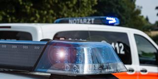 Ein Einsatzfahrzeug der Polizei steht mit Blaulicht an einem Unfallort, im Hintergrund sieht man Rettungsfahrzeug mit der Aufschrift Notarzt.  (Foto: IMAGO / Fotostand / Gelhot)